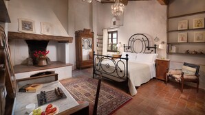 Een klassieke slaapkamer met een houten bed, een open haard, een schaakbord en een boekenkast.