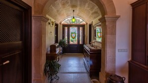 Un couloir doté d’un plafond en arc de cercle, d’une porte en bois et d’un vitrail.