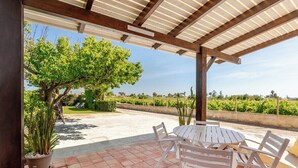 An outdoor patio with a round table and white chairs, surrounded by potted plants and a pergola structure. - House / Villa - MarsalaHouse with garden (Marsala)
