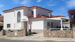 A two-story house with a red-tiled roof, white walls, and a stone wall entrance. - Luxury 4 bedroom villa with private pool on 5* golf & beach resort (Obidos)