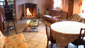 Un salon chaleureux avec une cheminée, un canapé, une table basse et une table à manger.