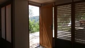 A room with a sliding door leading to a balcony with a view of a forested hillside. - House / Villa - Cargese (Cargèse)