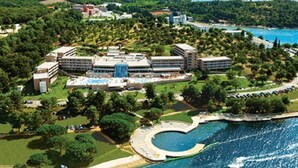 Vista aérea de un hotel con varias edificaciones, una piscina y un área ajardinada.