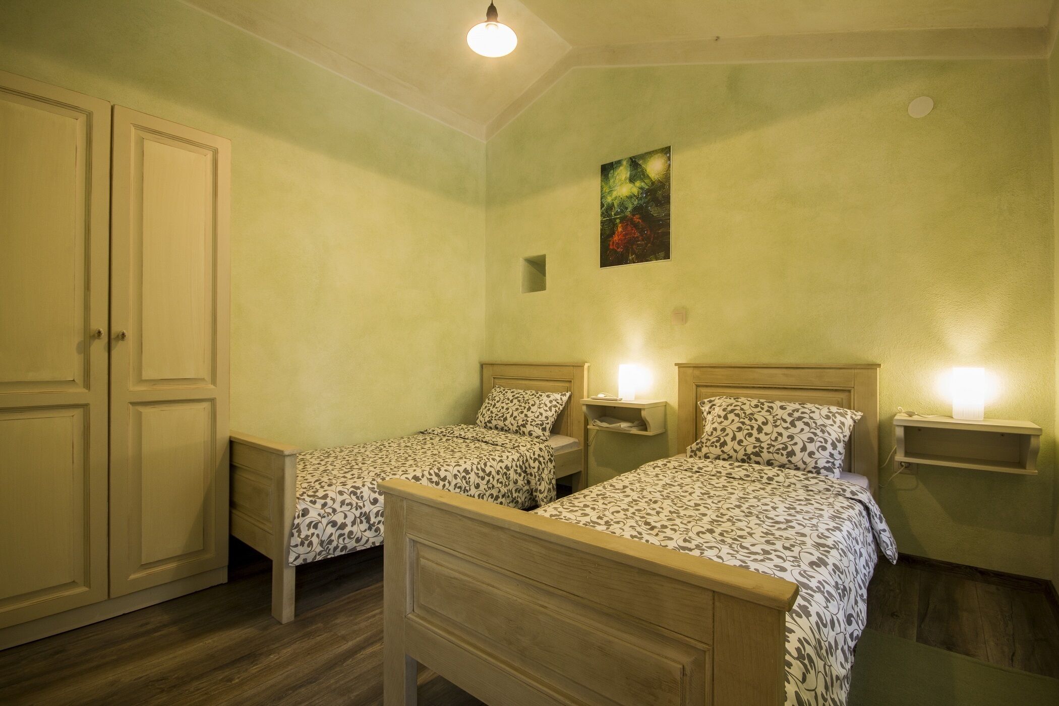 Une chambre avec deux lits simples, une armoire et un petit tableau accroché au mur.