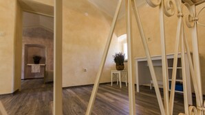 Una habitación amplia con piso de madera, una mesita con una planta y un estante blanco.