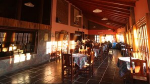 A spacious restaurant with high ceilings and wooden beams, featuring multiple tables and chairs, and large windows allowing natural light. - Hosteria Del Inca (Humahuaca)