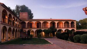 A courtyard with a tiled floor, surrounded by buildings with arched windows and a central open space. - Hosteria Del Inca (Humahuaca)
