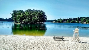 A sandy beach with a wooden bench and a lifeguard stand by the water. - Fairfield Plantation Resort (Villa Rica)
