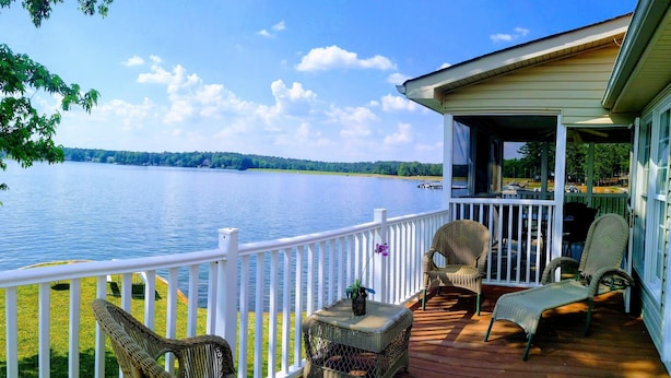 A wooden deck with wicker furniture overlooking a lake. - Fairfield Plantation Resort (Villa Rica)