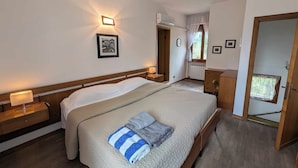 Une chambre bien éclairée, avec un lit, des tables de chevet, une commode et un miroir.
