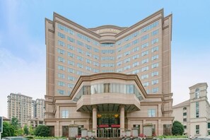 Un hotel grande de varios pisos con una entrada destacada y una fachada curva.