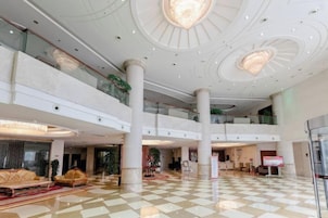 A spacious lobby with a checkered floor, multiple levels, and a central chandelier.