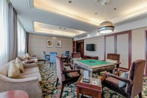 Une chambre d’hôtel équipée d’une table de billard, de fauteuils confortables, d’un téléviseur à écran plat et d’une grande fenêtre.
