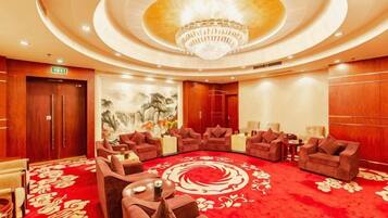 A hotel lobby with a circular seating area, a chandelier, and a red carpet.