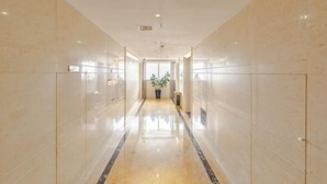 Un pasillo largo y estrecho con suelos y paredes reflectantes, que conduce a una puerta al final.