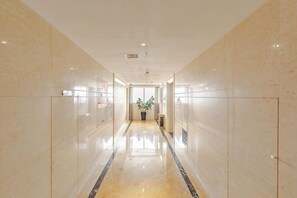 A long, narrow hallway with reflective floors and walls, leading to a door at the end.