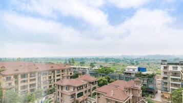 A residential complex with multiple apartment buildings, a swimming pool, and a view of the surrounding landscape.