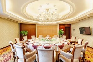 A conference room with a round table, chairs, a chandelier, and a carpeted floor.