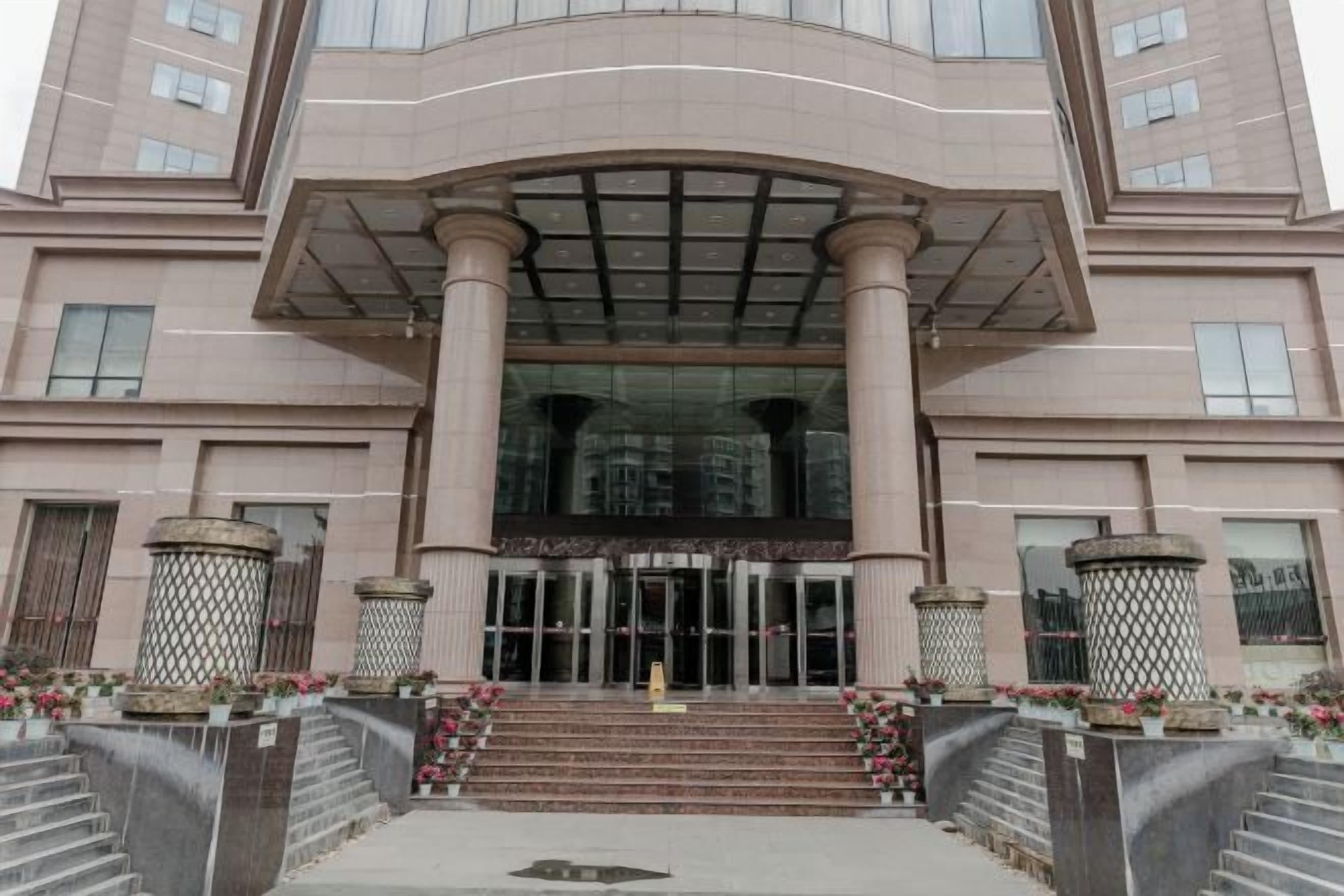 A multi-story building with a central entrance, large columns, and a glass facade.