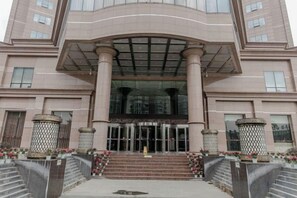 A multi-story building with a central entrance, large columns, and a glass facade. - Qingshen Hotel (Qingshen)