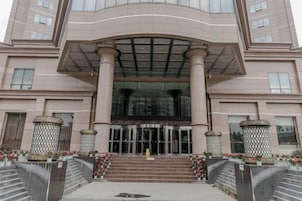 Un edificio de varios pisos con una entrada central, grandes columnas y fachada de vidrio.