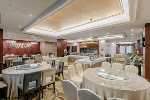 A hotel dining area with round tables, chairs, and a central bar area. - Qingshen Hotel (Qingshen)