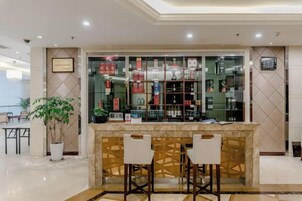 Una zona de bar con mostrador de mármol, dos taburetes y una vitrina con botellas.