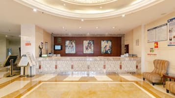 A hotel reception area with a marble floor, a reception desk, and a seating area.