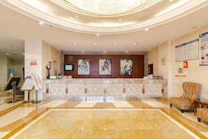 Zona de recepción de un hotel con suelo de mármol, un mostrador de recepción y un área de estar.