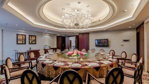 Una mesa redonda de comedor con sillas, una araña y un centro de mesa floral.