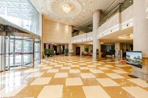 A spacious lobby with a checkered floor, a glass entrance, and a chandelier.