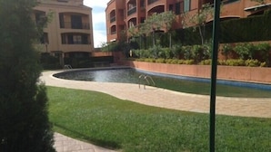 A landscaped courtyard with a curved pathway, a small water feature, and a building with balconies in the background. - Resting place. with possibilities of diverse distractions. (,L'Ametlla de Mar)