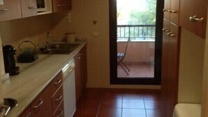 A narrow kitchen with wooden cabinets, a microwave, and a sink. There is a sliding glass door leading to a balcony with a view of greenery. - Resting place. with possibilities of diverse distractions. (,L'Ametlla de Mar)