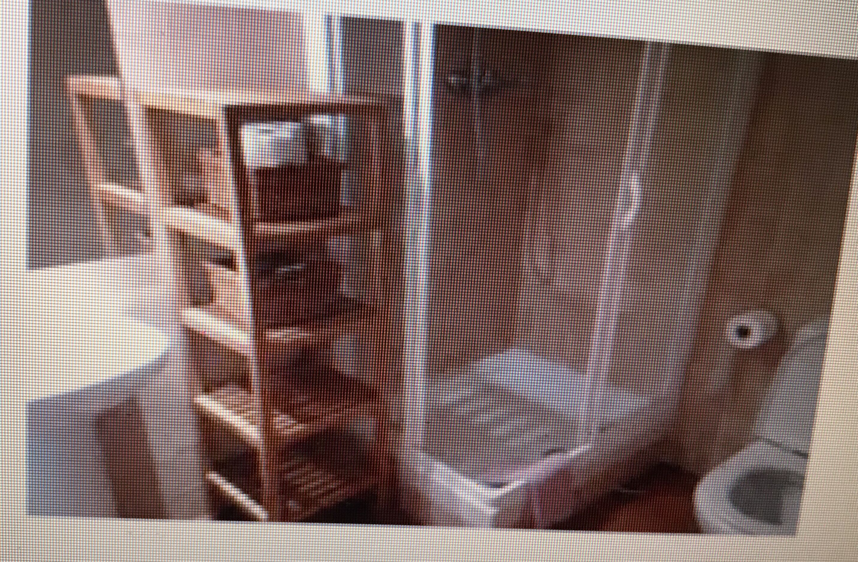 A bathroom with a toilet, sink, and shelving unit.