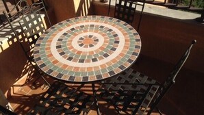 A round outdoor table with a mosaic tile design, surrounded by metal chairs. - Resting place. with possibilities of diverse distractions. (,L'Ametlla de Mar)