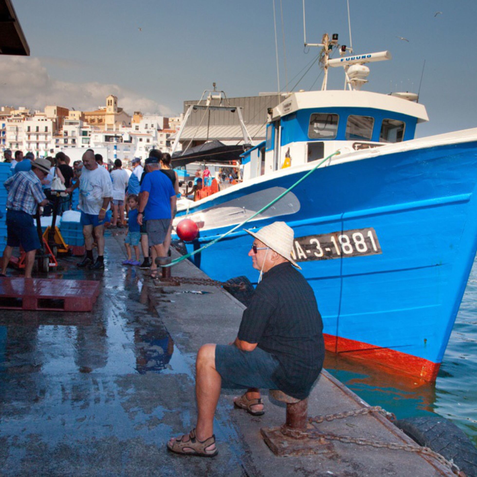 Un bateau bleu était amarré à un quai, et il y avait des gens autour.