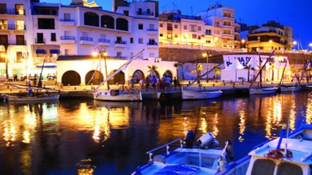 A marina with boats docked, a building with arches, and a tower. - Resting place. with possibilities of diverse distractions. (,L'Ametlla de Mar)