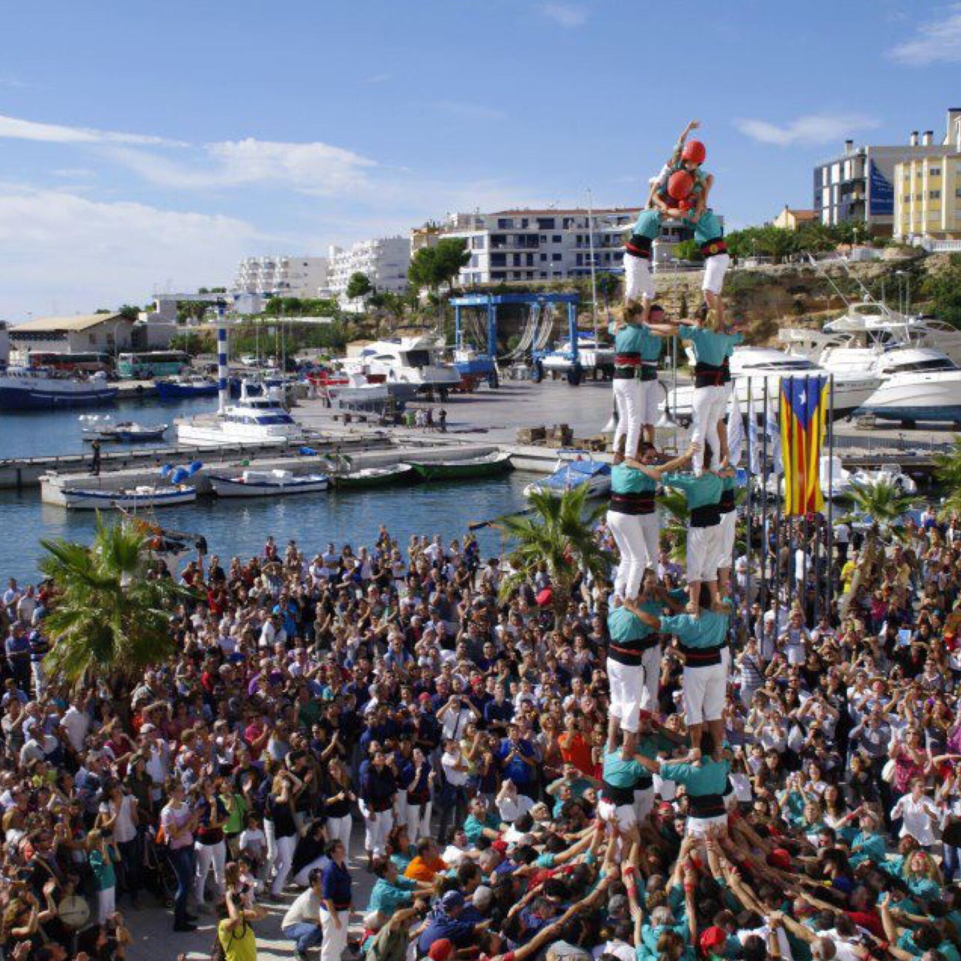 A group of people performing a synchronized act in a public square with boats and buildings in the background.