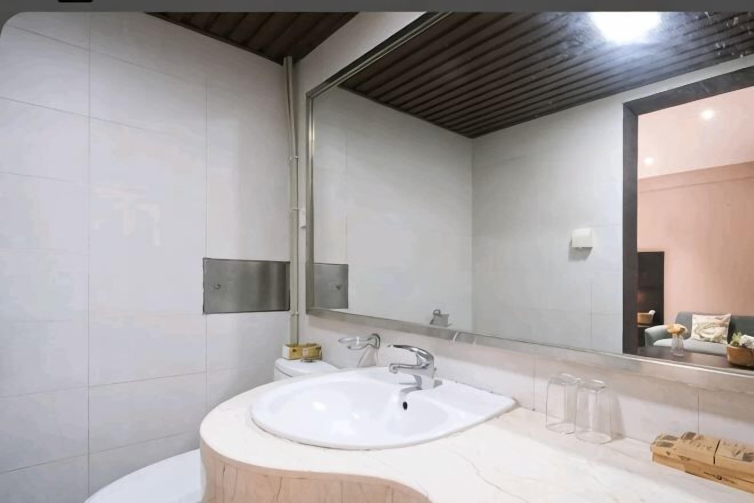 Ein modernes Badezimmer mit einem weißen Waschbecken, einem Spiegel und einer Holzausstattung.