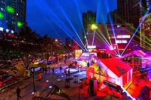 A brightly lit urban square with a prominent building featuring a red roof and illuminated signage. - Langfei Business Hotel (Chongqing)