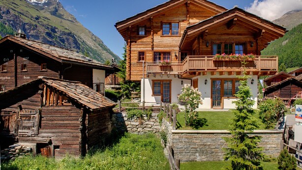 A traditional wooden chalet with a balcony, surrounded by lush greenery and mountains. - Chalet Ulysse Zermatt 4 guests /cosy/private garden/beautiful (Zermatt)