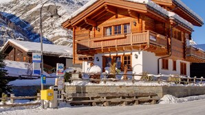 A wooden chalet with a balcony, surrounded by snow-covered mountains. - Chalet Ulysse Zermatt 4 guests /cosy/private garden/beautiful (Zermatt)