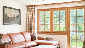 A living room with a brown leather sofa, a coffee table, and a painting on the wall. - Chalet Ulysse Zermatt 4 guests /cosy/private garden/beautiful (Zermatt)