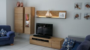 Una sala de estar moderna con un mueble de madera, un televisor de pantalla plana, un sofá azul y una réplica decorativa de un velero.