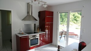 Una cocina moderna con armarios rojos, electrodomésticos de acero inoxidable y un ventanal grande.