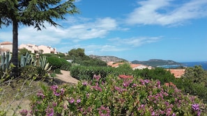 Paisagem costeira com edifícios, céu limpo e vista para o mar.