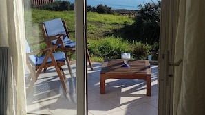 A bedroom with a sliding glass door leading to a balcony with a view of the sea.
