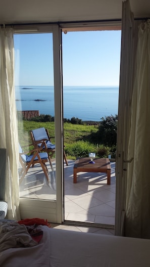 Quarto com porta de vidro deslizante que dá para uma varanda com vista para o mar.