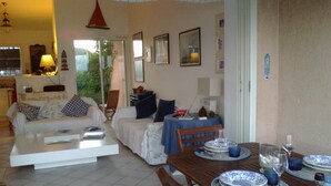 A living room with a sofa, a dining table set with plates and glasses, and a chair.