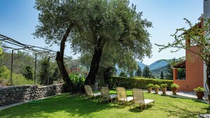 A patio with outdoor furniture, a large tree, and a view of mountains. - Stathis House - Ag. Georgios Corfu (Pagi)